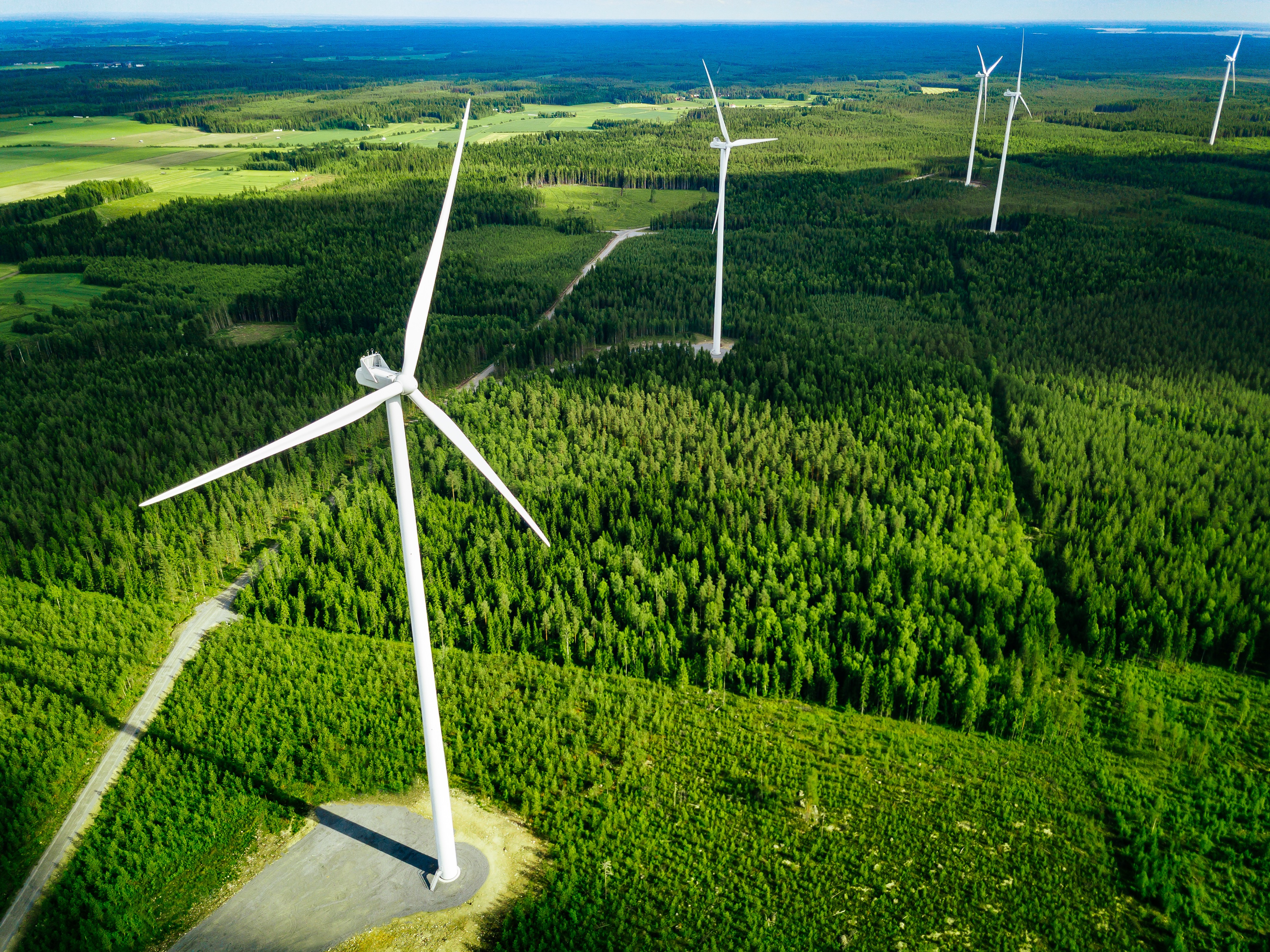 https://watt.co.uk/wp-content/uploads/2020/04/aerial-view-of-windmills-in-summer-forest-in-finla-9PBN584.jpg